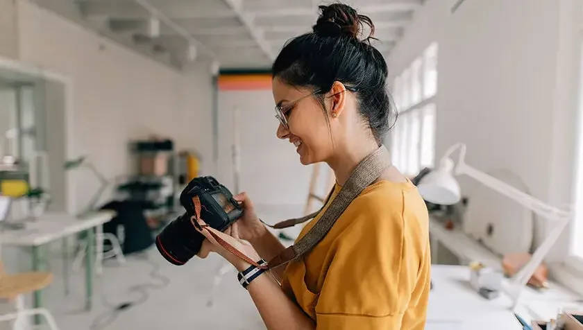 woman photographer taking pictures in her studio in yellow shirt 