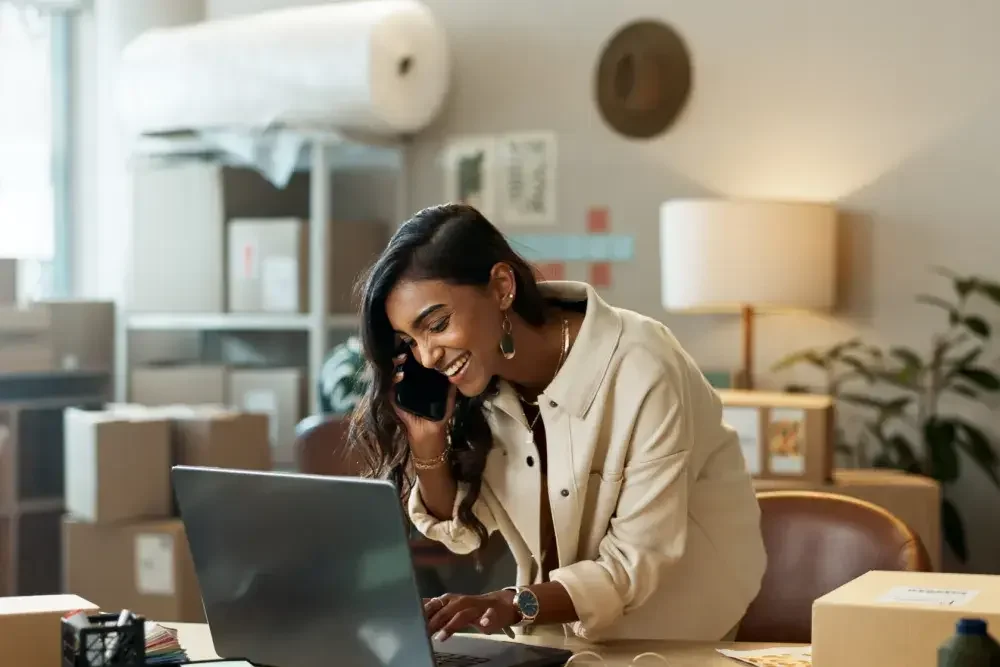 A business owner talks on the phone while looking up something on her laptop in her office. An available business name may be reserved in Illinois for 90 days for a $25 fee by filing Form LLC-1.15.