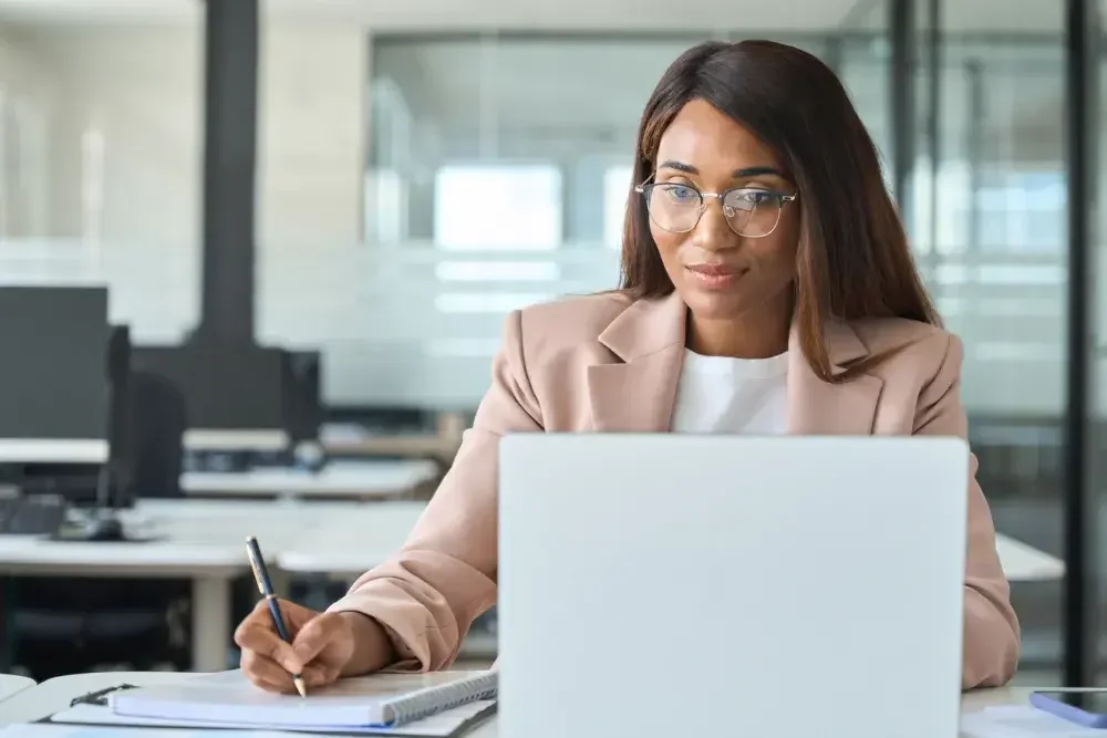 The owner of a consulting firm takes notes while reading about LLC business taxes.  If her LLC is taxed as an S corporation, her business doesn't pay corporate income tax. Instead, the LLC's profits pass through to the members, who report and pay tax on them when they file their personal income tax returns.