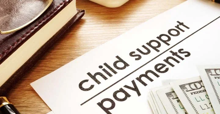 Hundred dollar bills on a piece of paper labeled "child support payment"