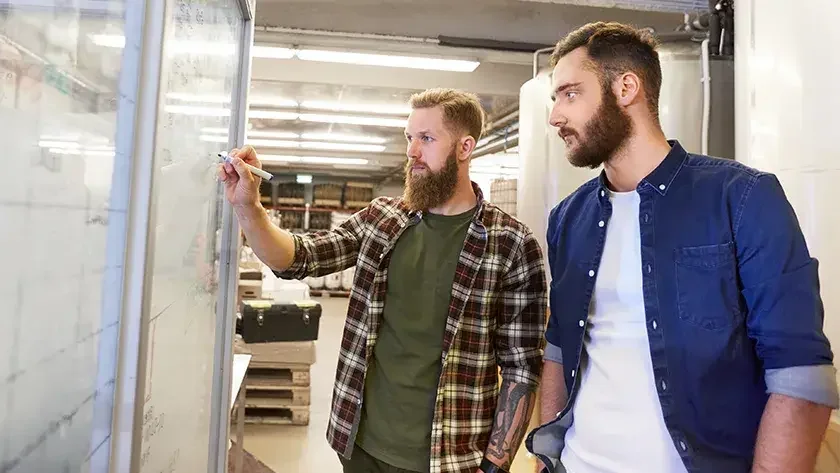 men in a conference room writing on a whiteboard 