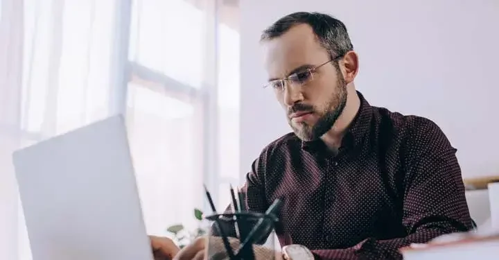 Man with glasses looking at his laptop