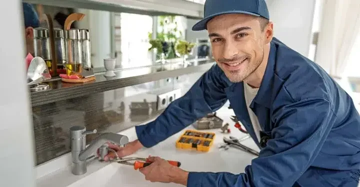 Man in kitchen using tools to fix sink