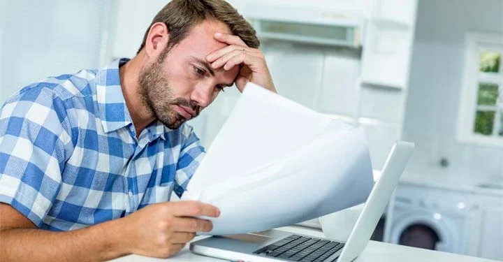 Frustrated man reading paperwork