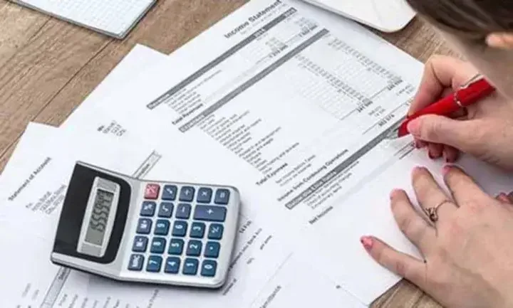 Woman using a calculator and pen to complete an income statement