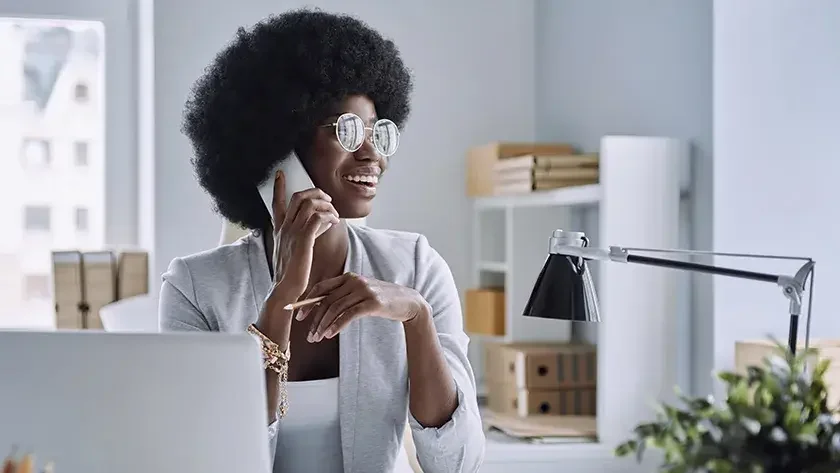 woman sitting at desk talking on the phone 