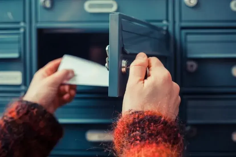 A person takes mail out of a personal U.S. P.O. Box at a post office.