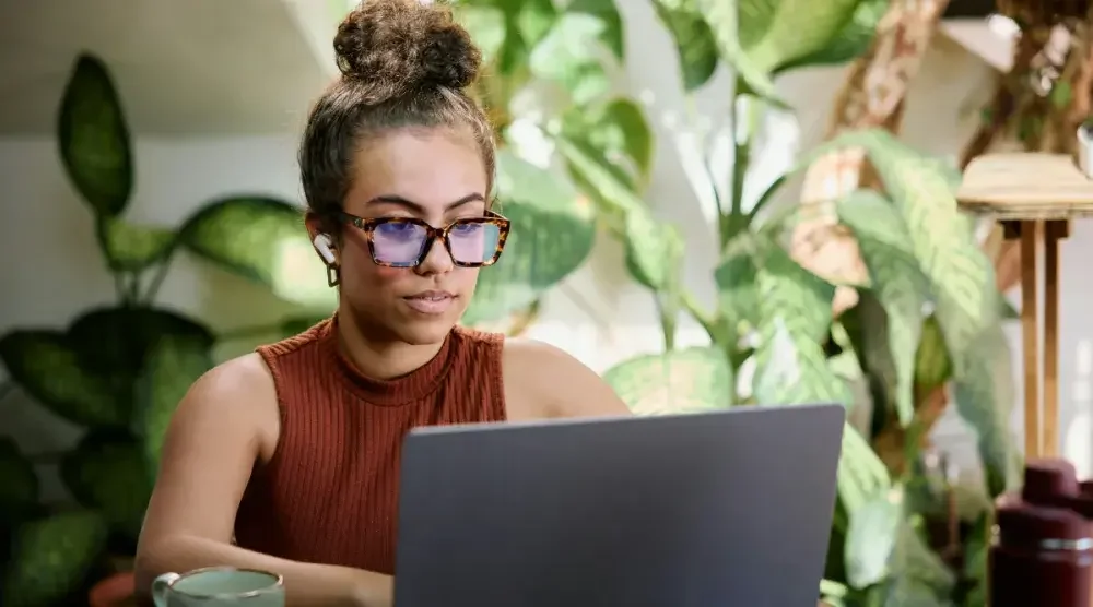 A woman sits at her desk surrounded by plants and reviews her trademark application.