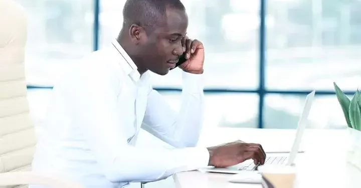 Man talking on the phone while using his laptop