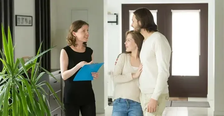 Woman and couple standing in a home reviewing paperwork