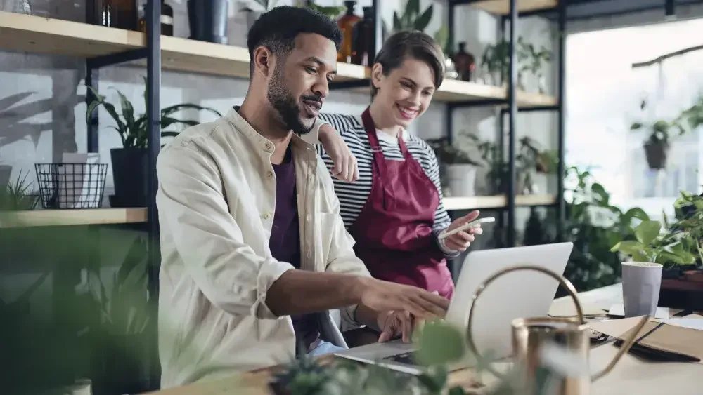 coworkers looking at laptop in flower shop