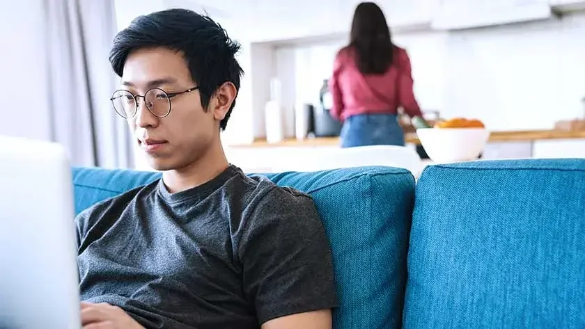 man-sitting-on-sofa-looking-at-laptop