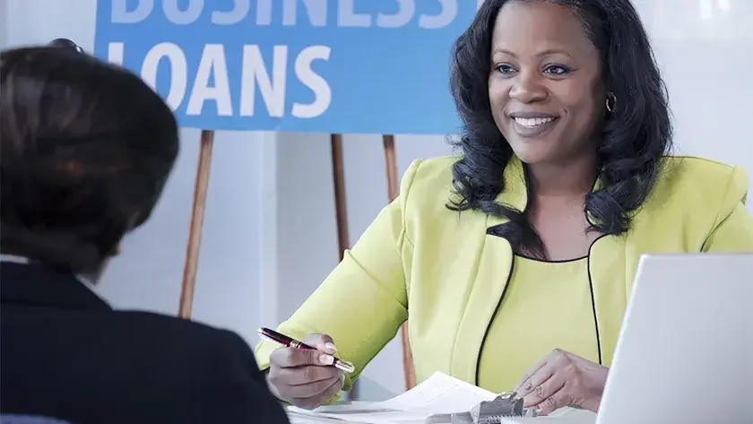 woman in yellow and black business suit smiling over paperwork