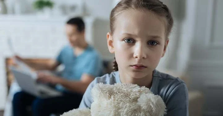 Little girl looking sad and holding a teddy bear