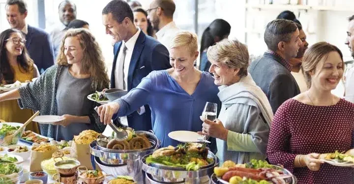 Smiling people serving themselves at buffet and chatting