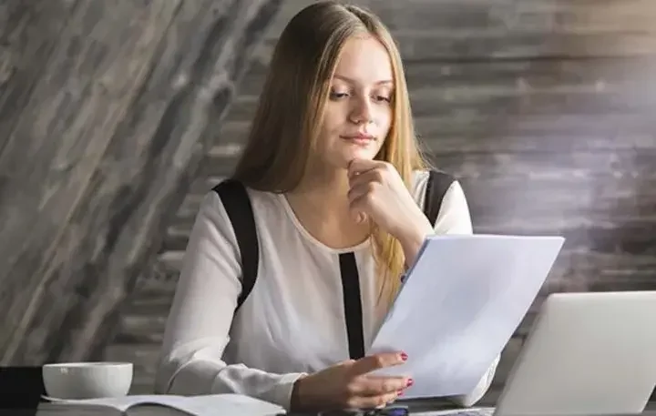 Ray of light illuminating sheet of paper sad woman contemplates over cup of coffee and book