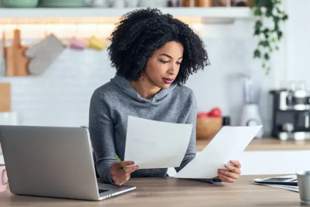 A young woman seated at a counter looks over documents to change her name on her Social Security card. Name changes may be granted for marriage, divorce, gender transformation, or more.