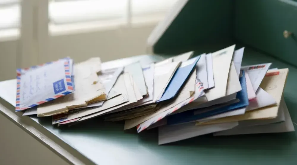 A stack of letters fanned out on an old-style wooden letter desk.