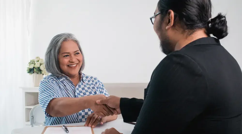 A woman shakes her lawyer's hand after signing a power of attorney.