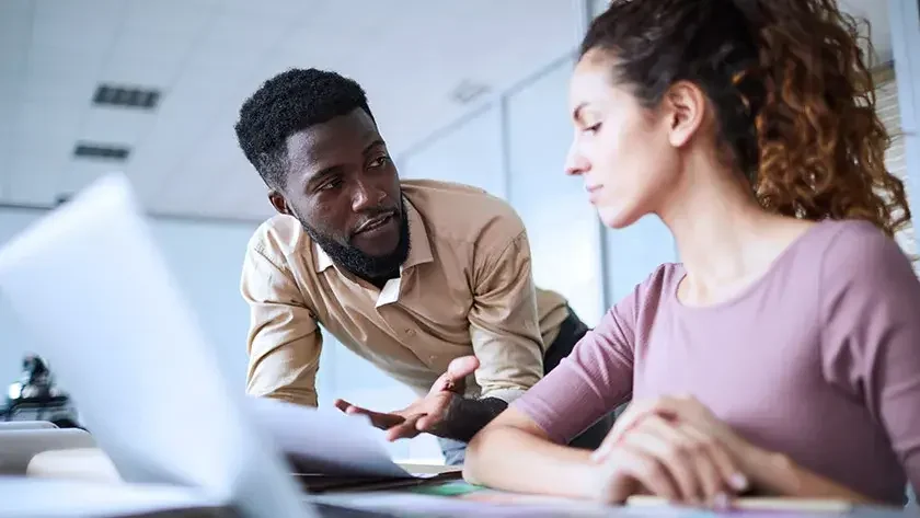 Man and woman colleagues have a conversation over paperwork