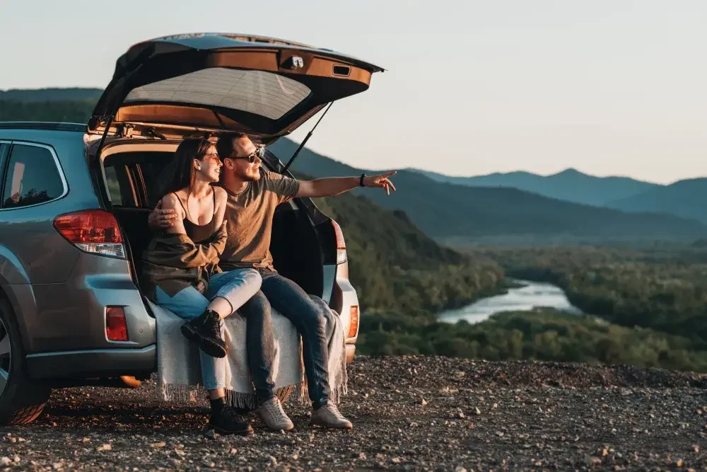 A woman and man sit on the back bumper of their SUV as they discuss where to build their next business.