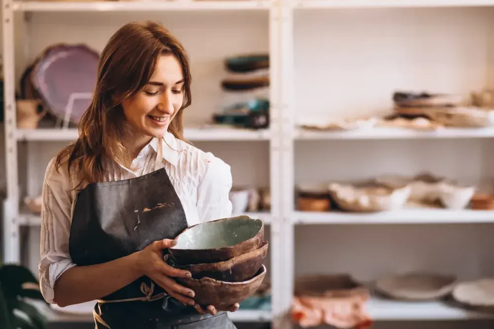 A woman in an apron holds ceramic bowls in her pottery shop. Florida LLCs are required to file an annual report.