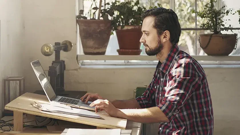 man looking at laptop in his workshop