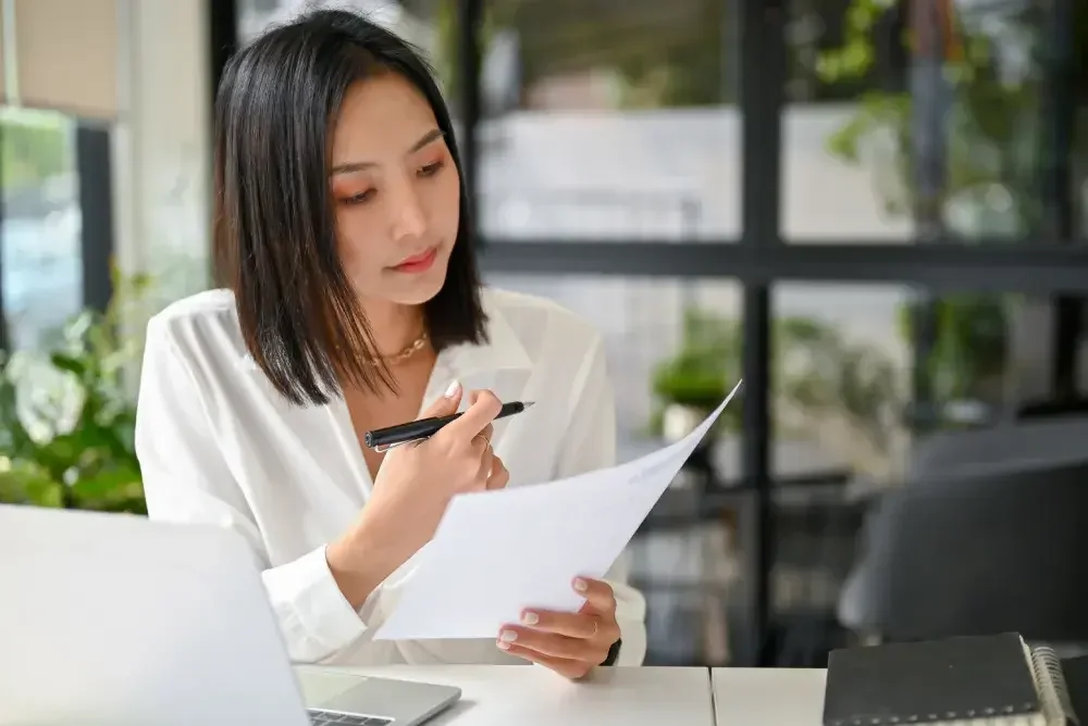 A woman seated at a desk holds a printout of a page from the Corporate Transparency Act, which goes into effect Jan. 1, 2024. Millions of business owners will be affected.