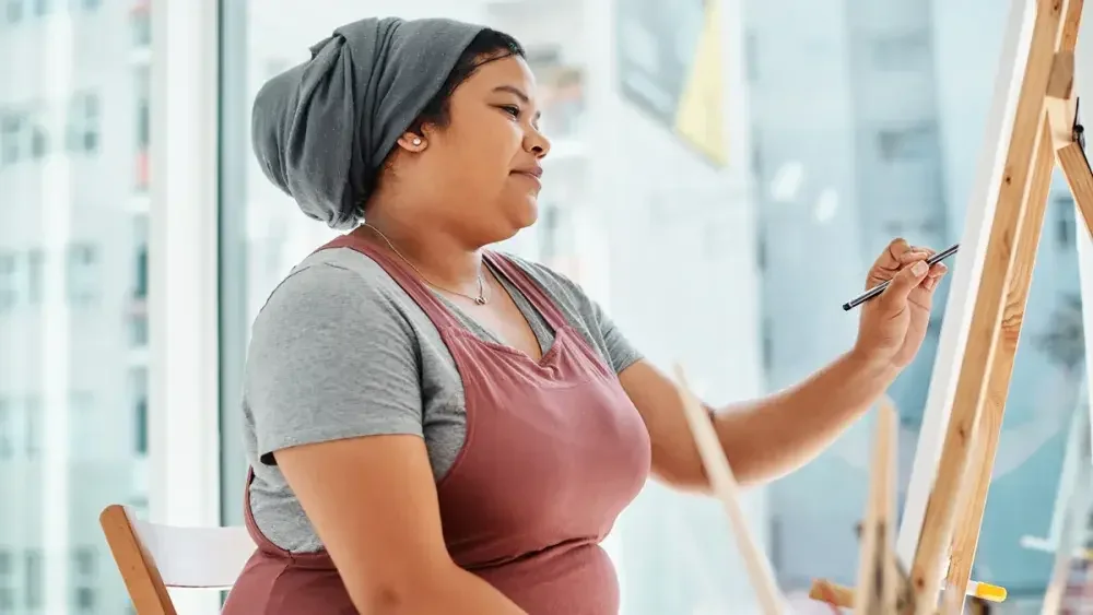 A woman paints on an easel. You might not realize that hobby income is taxable in the eyes of the IRS.