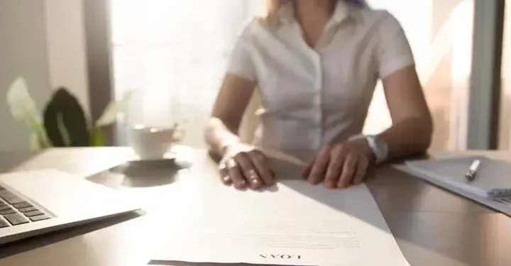 Woman sitting at a desk with her hands on a piece of paper entitled "Loan"