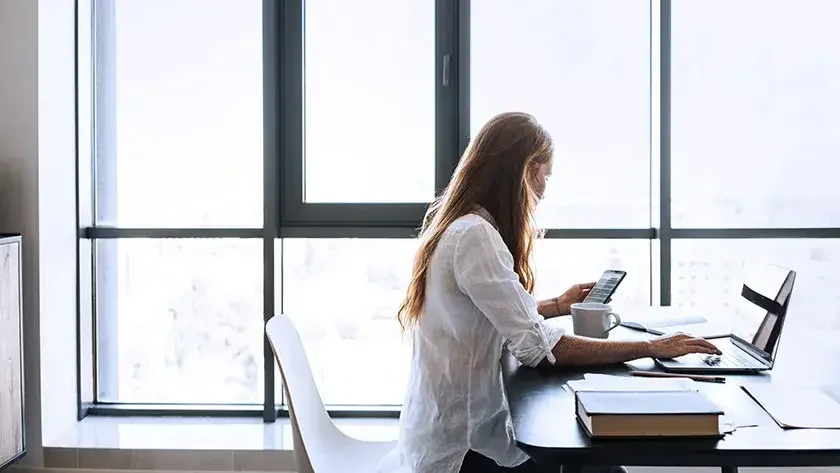 Woman working on laptop by window