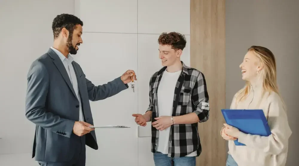 A property manager hands a young couple the keys to their new apartment.