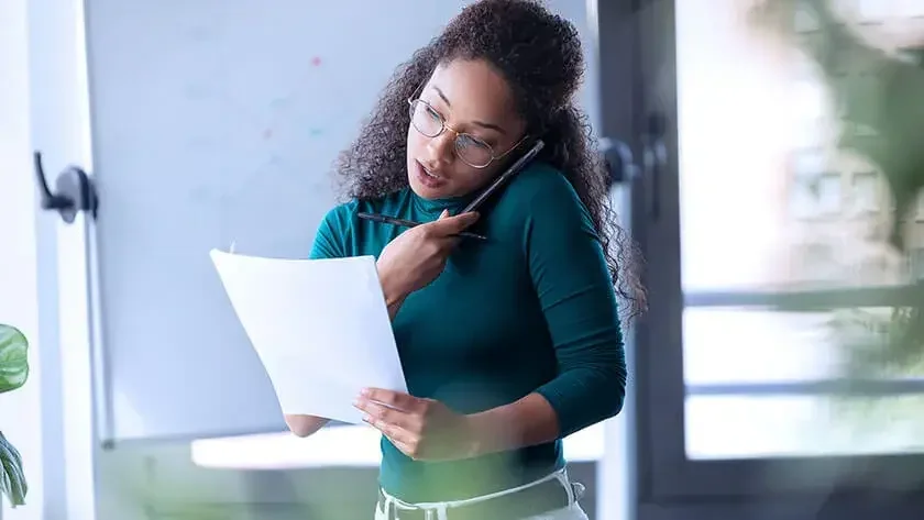 woman-on-phone-looking-over-documents wearing green shirt