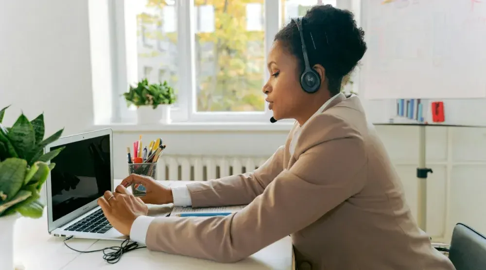 A woman with headphones on types on her laptop. The executor of an estate should be trustworthy, patient and have financial experience.