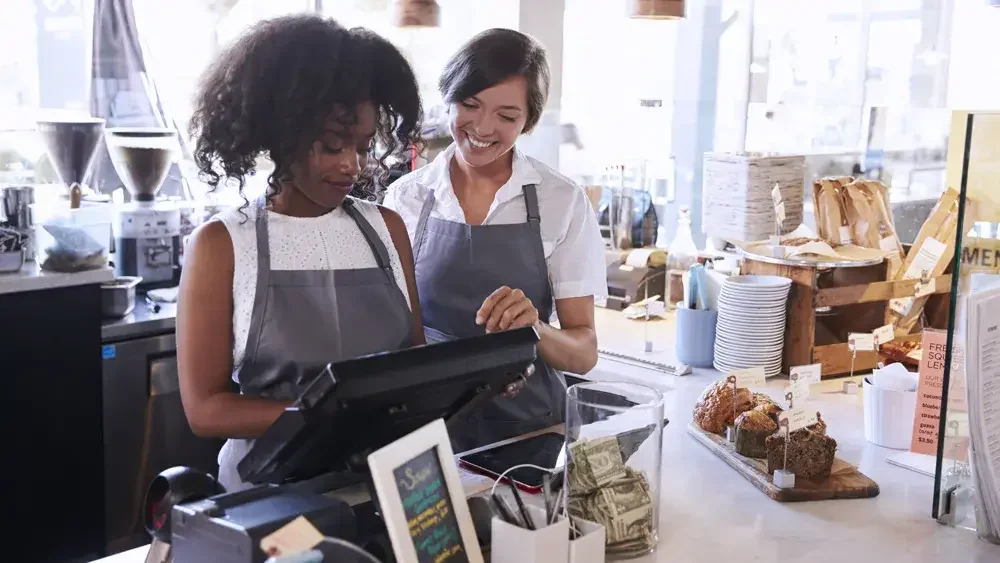 two women working at a register in a café 