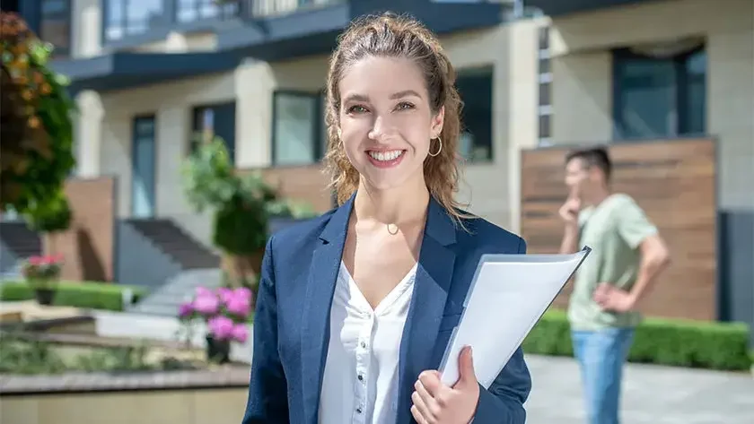 A smiling landlord holds a lease agreement in her hand