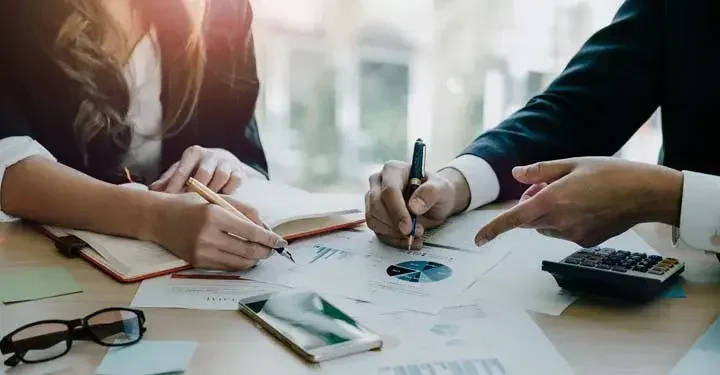 Businesswoman and businessman sitting at a table reviewing paperwork