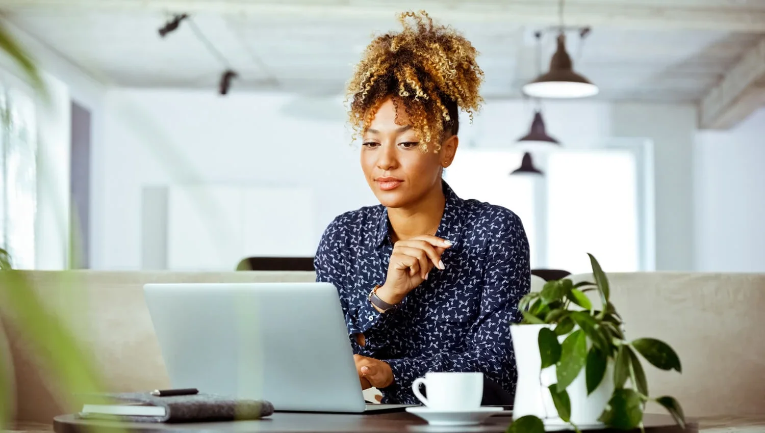 blonde woman in polka dot shirt looking at laptop