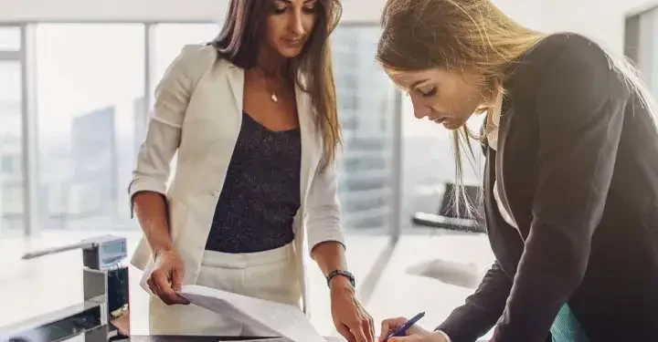 Businesswomen signing documents