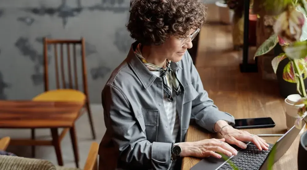 A woman is sitting at a desk in front of a laptop researching what it means to work as or hire an independent contractor