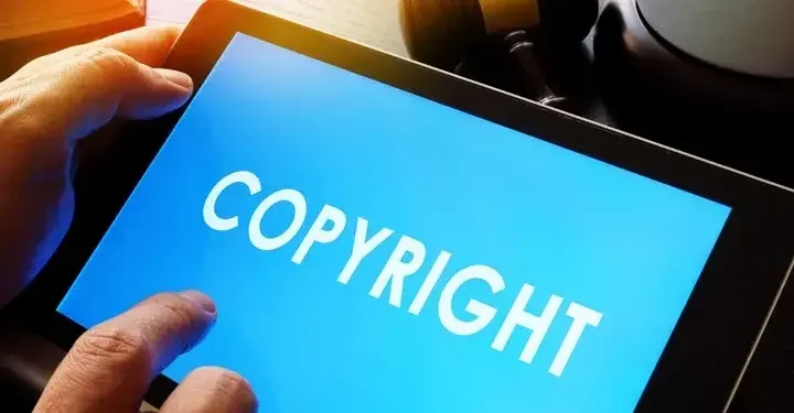 Hands holding a tablet with the word "copyright" displayed on the screen