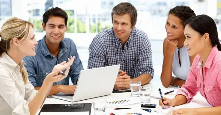 Businesspeople gathering around table and smiling while they talk