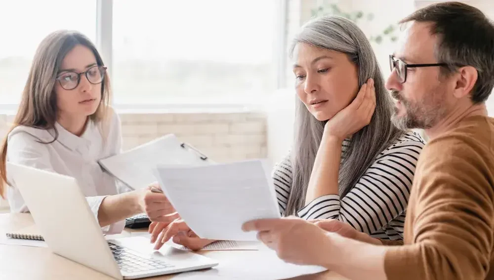 Three LLC members gather around a table to consider filing LLC taxes as an S corporation.