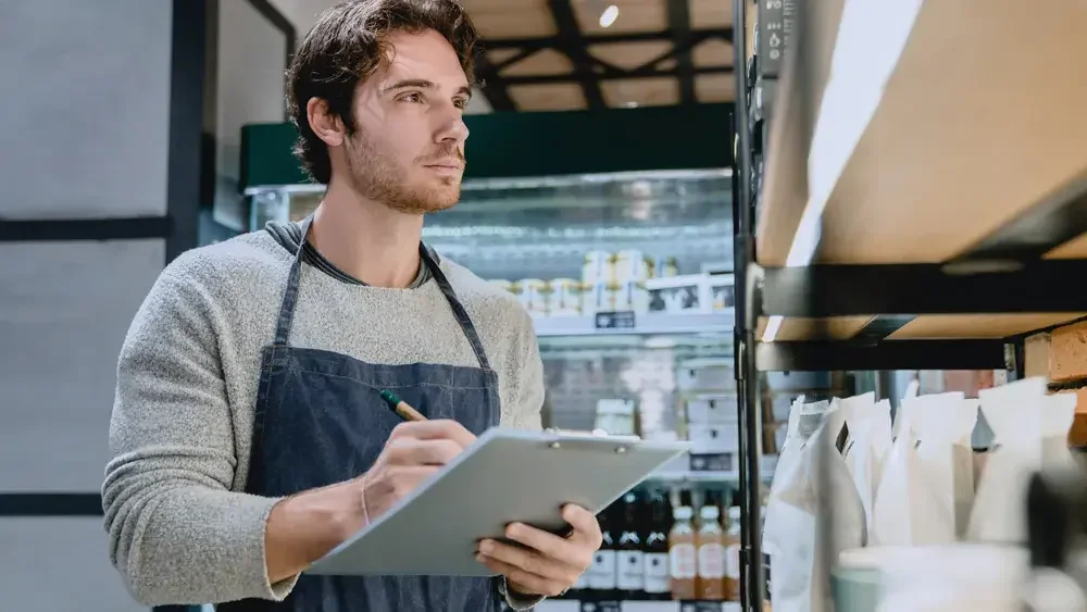 man wearing apron taking inventory 