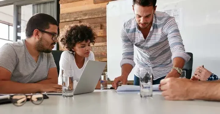 Young coworkers looking at laptops and paperwork on a desk