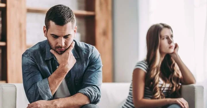 Man and woman sitting on opposite ends of a couch