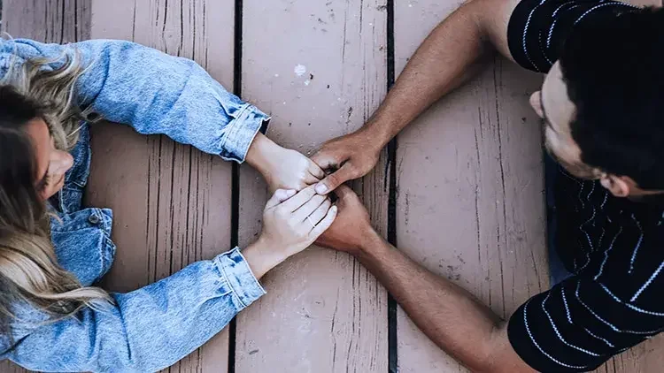 Woman and man holding hands across table