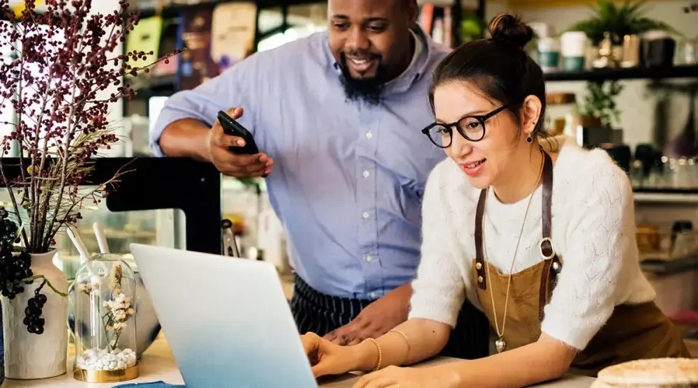 A woman and a man look at a laptop computer.  All business owners should find out if they need to fill out a beneficial ownership report.