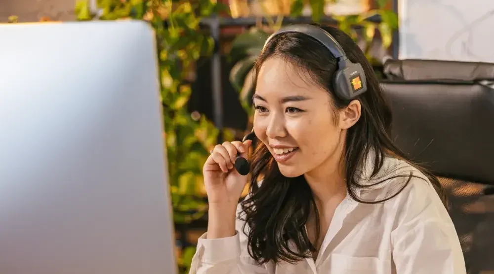 A woman uses a headset while sitting at a desk in front of a desktop computer screen. She is discussing a commercial lease for her small business. 