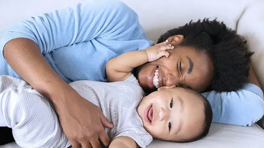 mother-lying-down-holding-baby-smiling